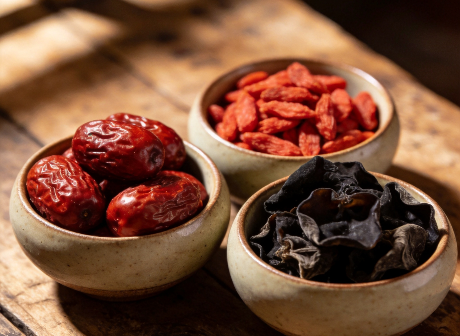 Dried red dates, goji berries and black fungus in ceramic bowls